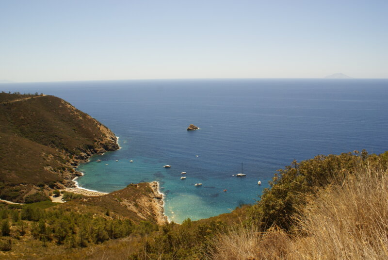 Einsame Bucht auf der Insel Elba mit Sandstrand, blauem Wasser und einem Segelboot.