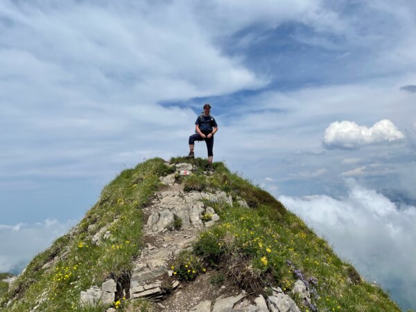 Wanderer auf Berggipfel steht da wie Wilhelm Tell.