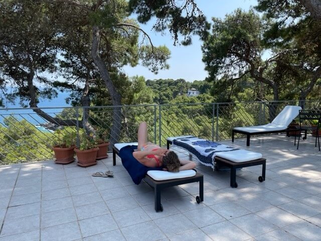 Hotelterrasse mit Liegestühlen und herrlicher Aussicht auf Pinienwälder und das Meer