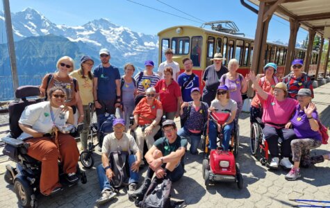 Procap-Reisegruppe in Interlaken, Zug und Berge im Hintergrund