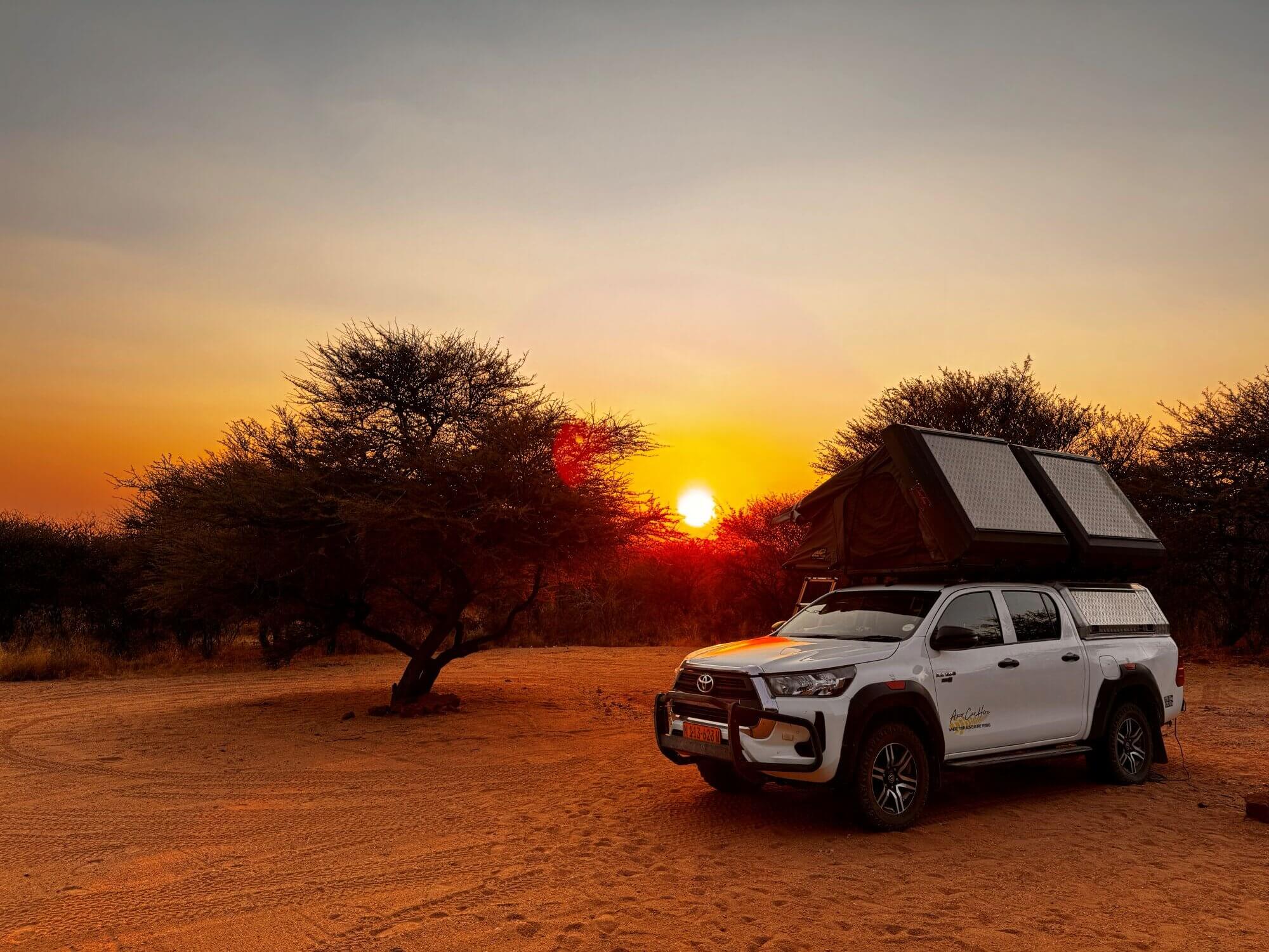Auto mit Dachzelt bei Sonnenaufgang in Okonjima, Namibia