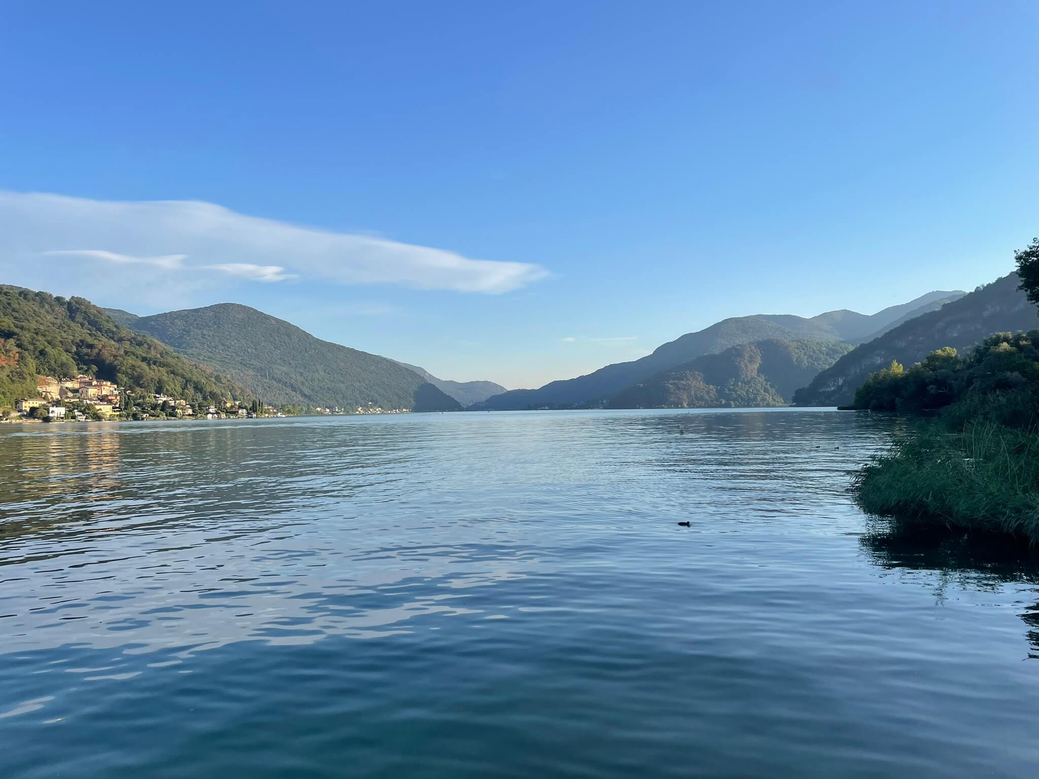 Der Blick auf den Luganersee mit grünen Bergen im Hintergrund