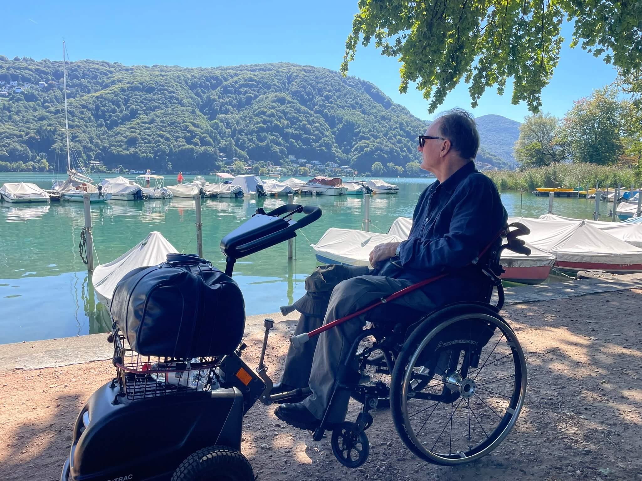 Alex Oberholzer mit Gepäck vor Booten im Luganersee