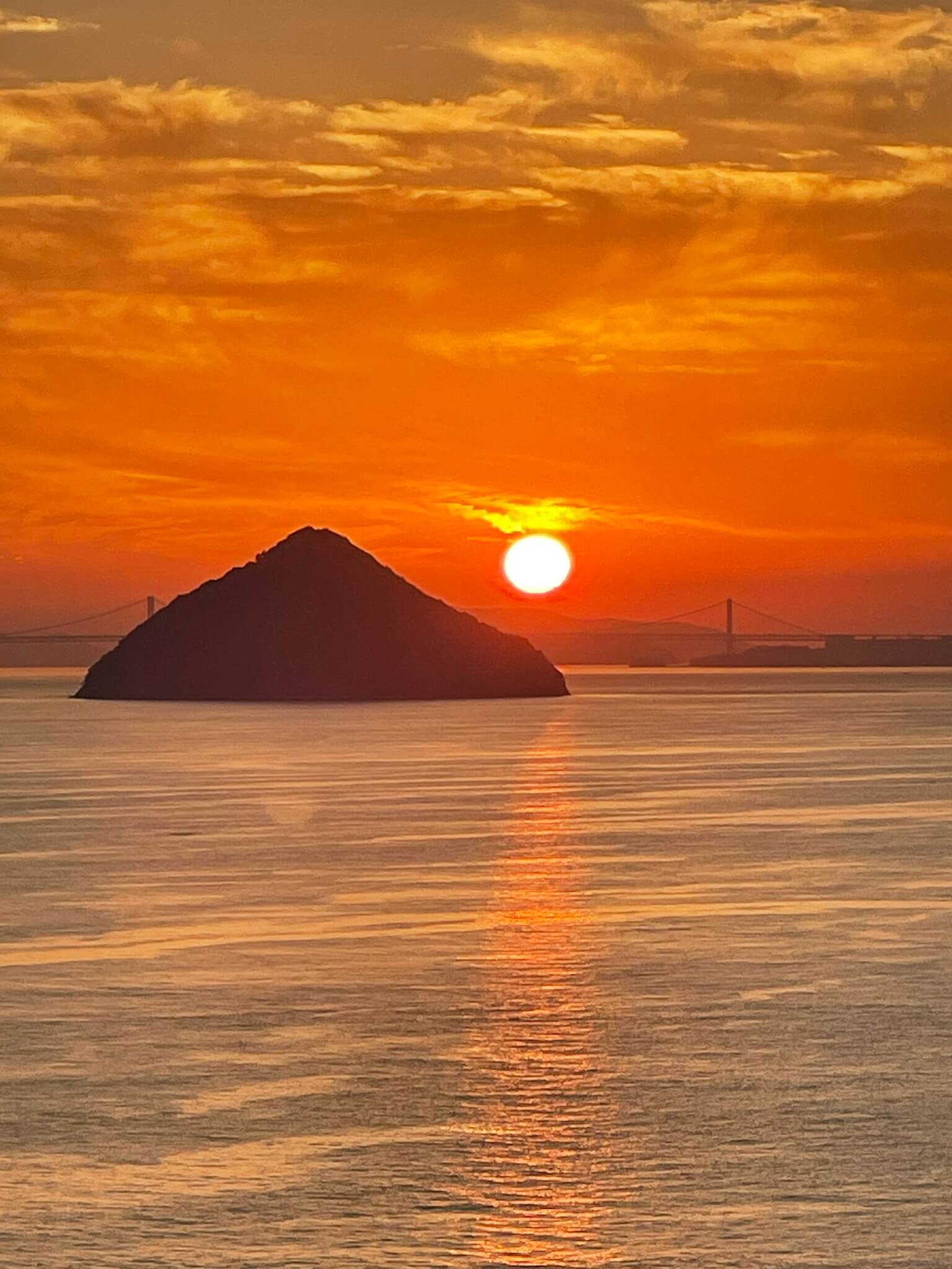 Sonnenuntergang über dem Meer und einer pyramidenförmigen Insel auf Naoshima