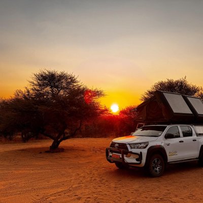 Auto mit Dachzelt bei Sonnenaufgang in Okonjima, Namibia